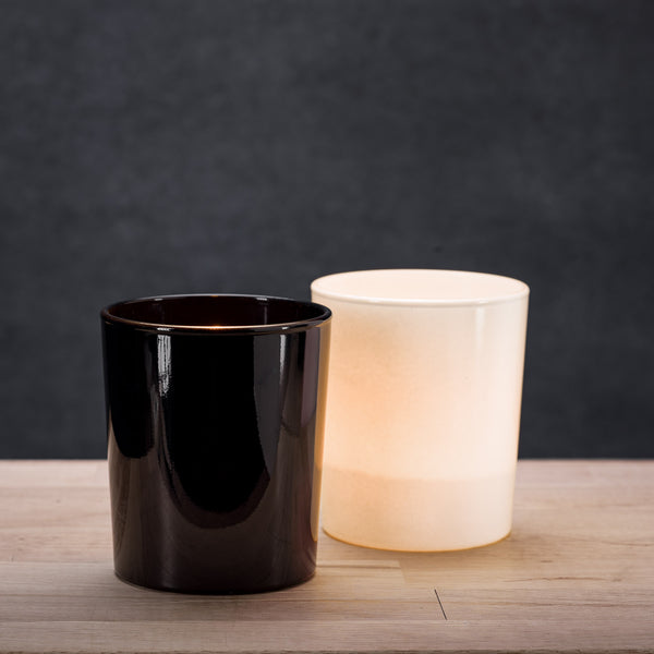 Zestaw czarnych i białych pojemników szklanych z połyskiem w świetle świec