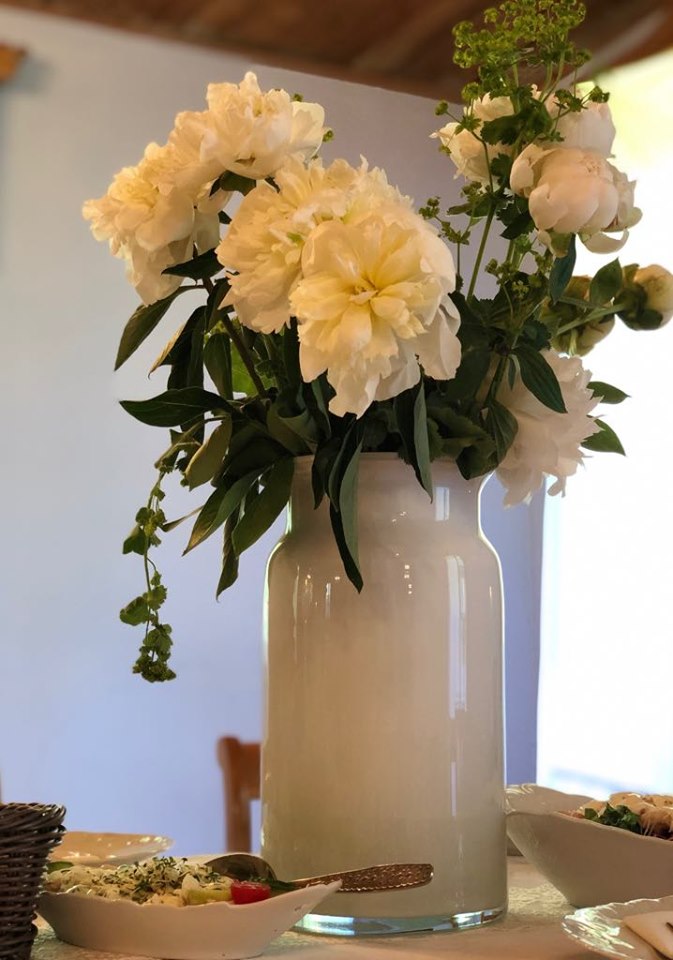 Białe kwiaty umieszczone w wysokim wazonie w kształcie słoja