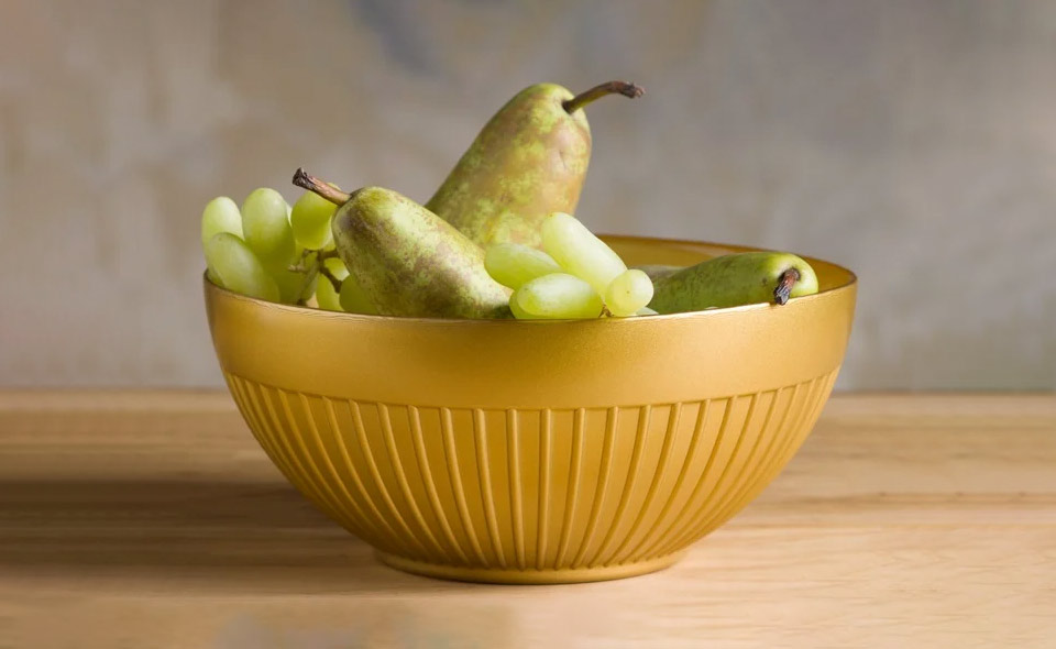 Zestaw złotych salaterek szklanych na drewnianym stole z owocami
