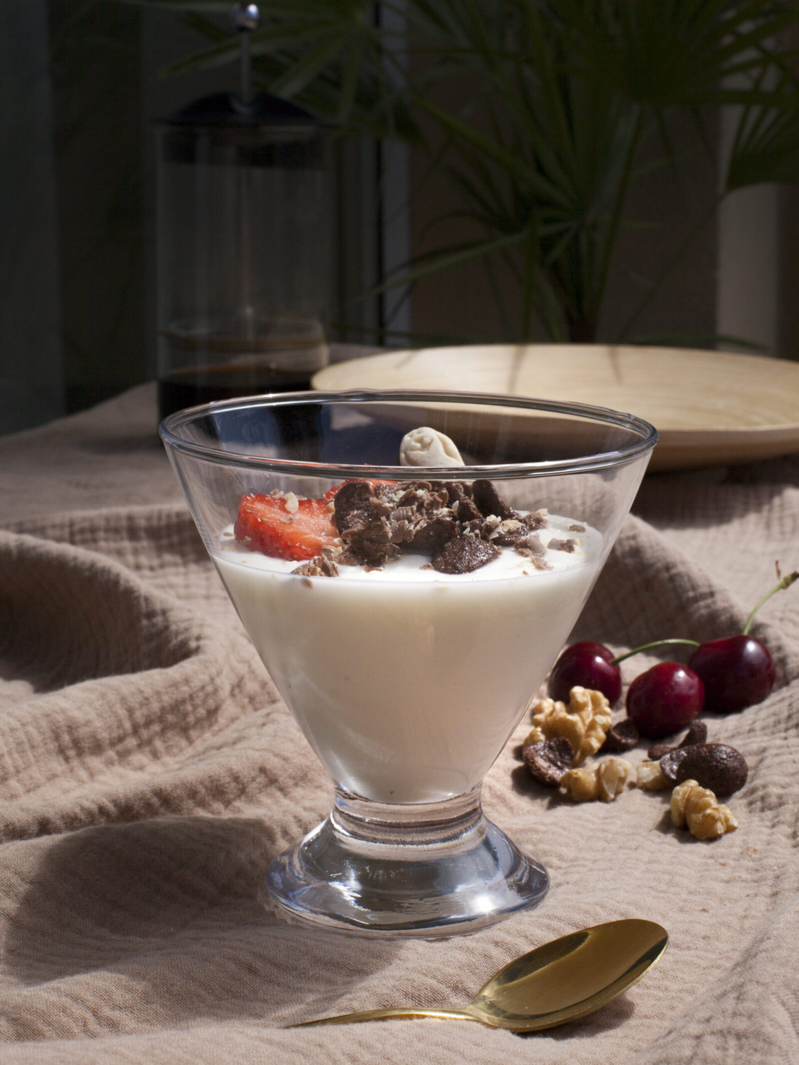 Szklany pucharek z jogurtem udekorowany owocami i płatkami