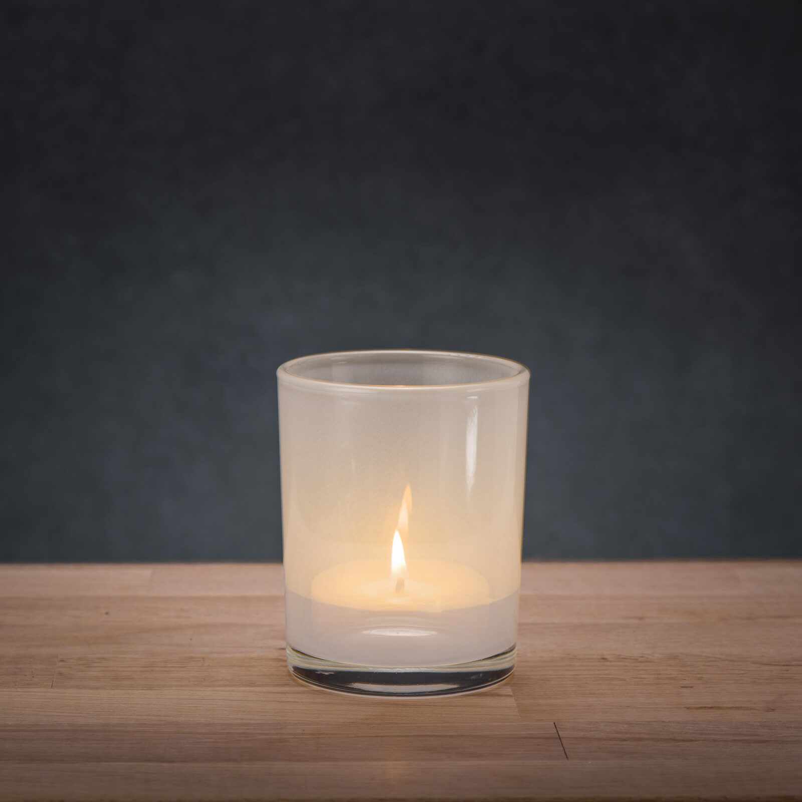 Zapalona świeczka w szklanym transparentnym pojemniku białym
