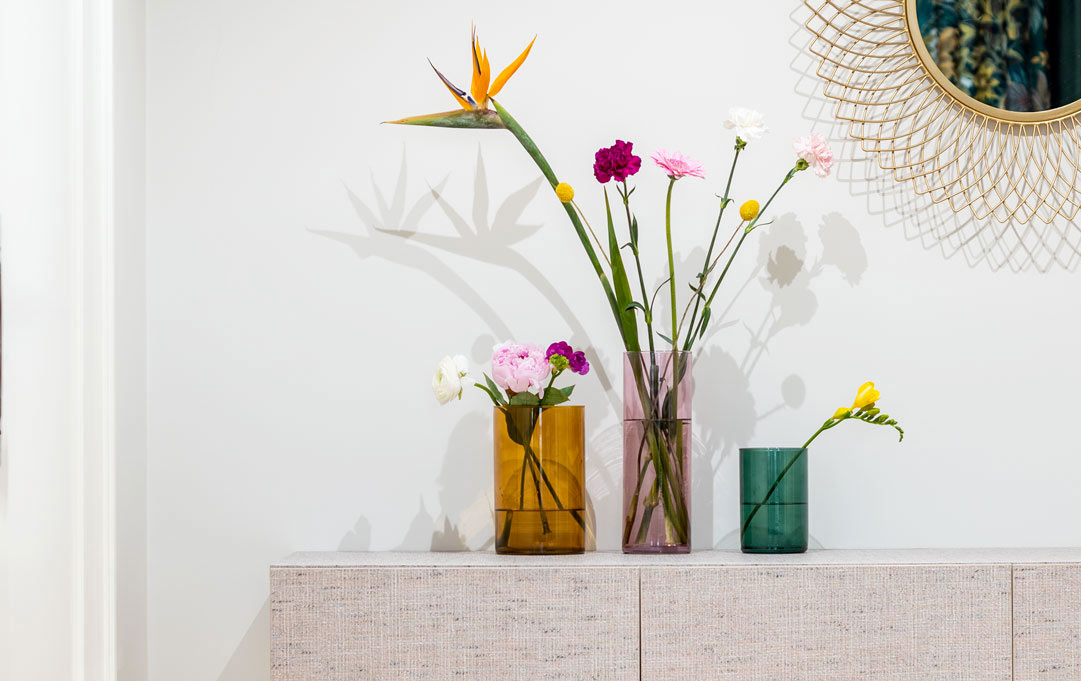 Wazony szklane różnokolorowe z kwiatami na eleganckim stole
