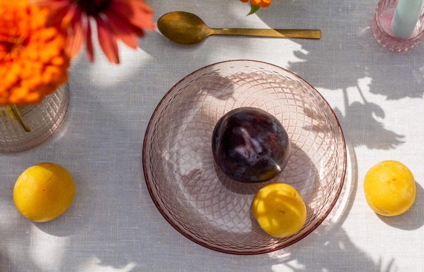 Talerzyk deserowy szklany z kolorowego szkła na stole w ogrodzie z owocami